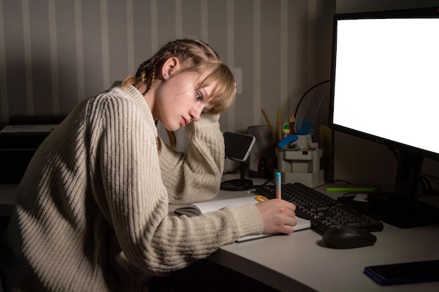 Adolescente carina di notte che si prepara per gli esami Scrivi una sinossi vicino al computer di notte