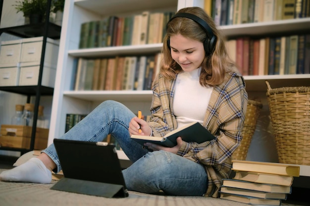 Adolescente che fa i compiti a una scrivania nella sua camera da letto ragazza adolescente studente di scuola scrivere note guardare video webinar online imparare sul computer portatile corso di elearning a distanza videoconferenza chiamata al pc
