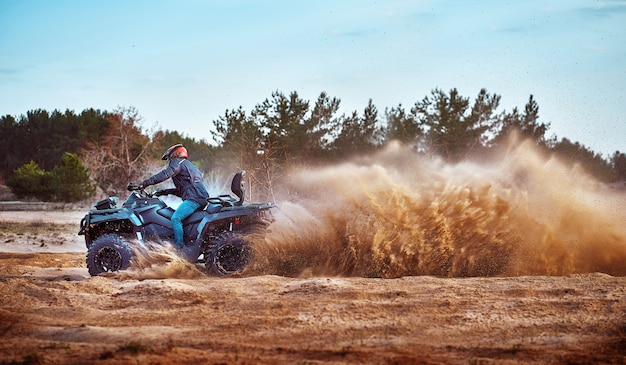 Adolescente che guida l'ATV nelle dune di sabbia che fa un giro nella sabbia