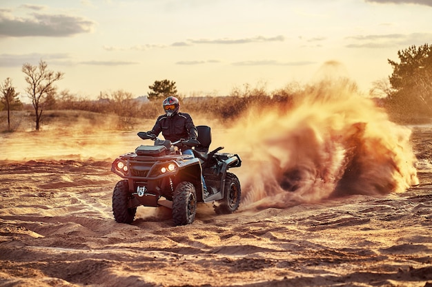 Adolescente che guida l'ATV nelle dune di sabbia che fa un giro nella sabbia