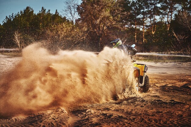 Adolescente che guida l'ATV nelle dune di sabbia che fa un giro nella sabbia