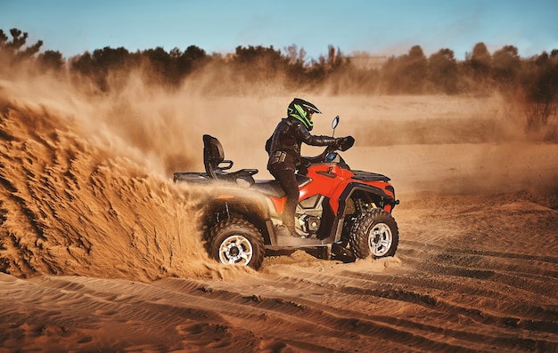 Adolescente che guida l'ATV nelle dune di sabbia che fa un giro nella sabbia