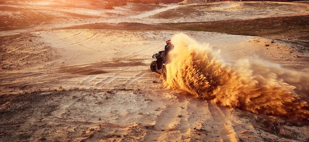 Adolescente che guida l'ATV nelle dune di sabbia che fa un giro nella sabbia