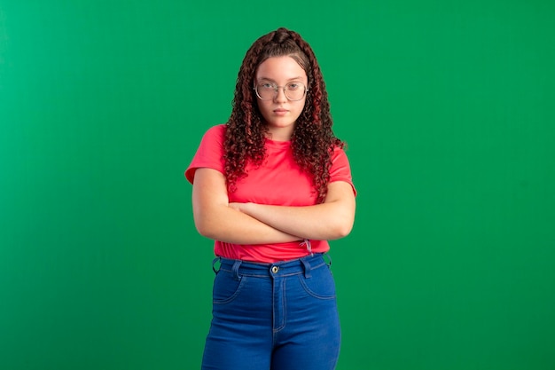 Adolescente che indossa occhiali in pose divertenti in una foto in studio con uno sfondo verde ideale per il ritaglio