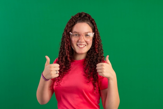 Adolescente che indossa occhiali in pose divertenti in una foto in studio con uno sfondo verde ideale per il ritaglio