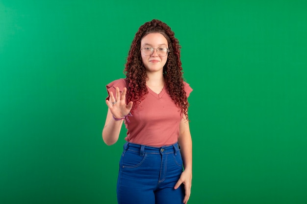Adolescente che indossa occhiali in pose divertenti in una foto in studio con uno sfondo verde ideale per il ritaglio