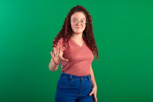 Adolescente che indossa occhiali in pose divertenti in una foto in studio con uno sfondo verde ideale per il ritaglio