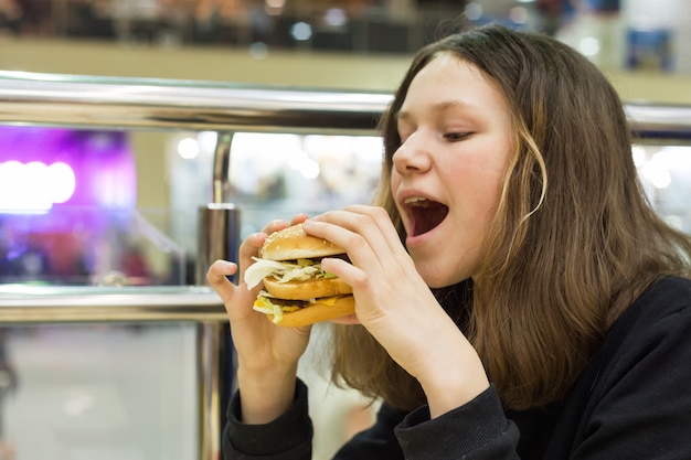 Adolescente che mangia hamburger