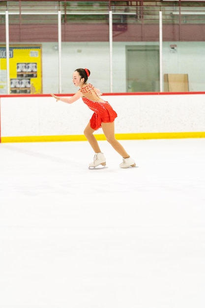 Adolescente che pratica il pattinaggio artistico su una pista di pattinaggio su ghiaccio al coperto