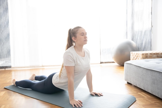 Adolescente che pratica yoga su una stuoia a casa