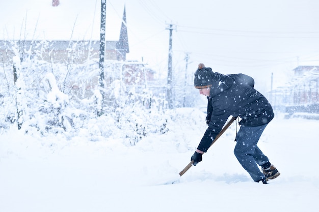 Adolescente che rimuove neve con una pala in inverno