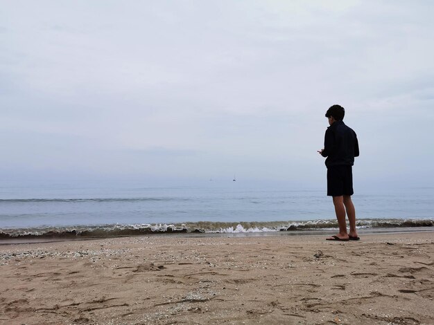 Adolescente che scatta fotografie sulla spiaggia. Utilizzo di dispositivi elettronici