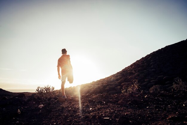 Adolescente che si estende in montagna al tramonto - vita da corridore e concetto sportivo - stile di vita all'aperto