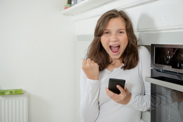 Adolescente che utilizza smartphone nella cucina