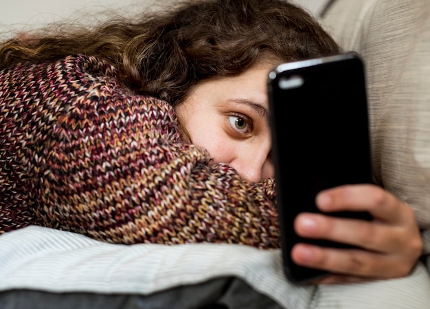 Adolescente che utilizza uno smartphone su un letto