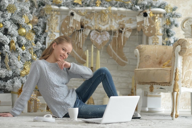 Adolescente con il computer portatile sul pavimento a Natale