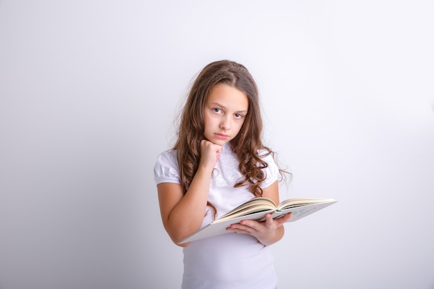 Adolescente con un libro in mano su uno sfondo bianco Mostra emozioni gioia sorpresa tristezza