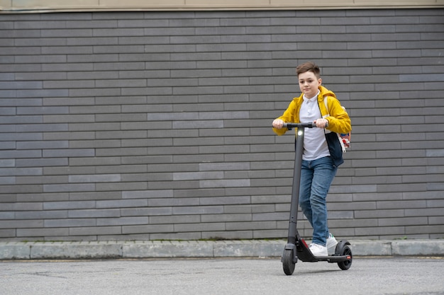 Adolescente con zaino cavalca su scooter elettrico