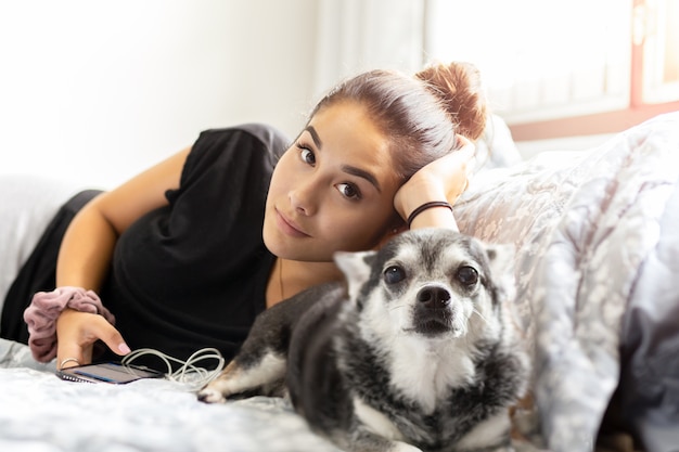 Adolescente della corsa mista che indica a letto con il suo cane della chihuahua