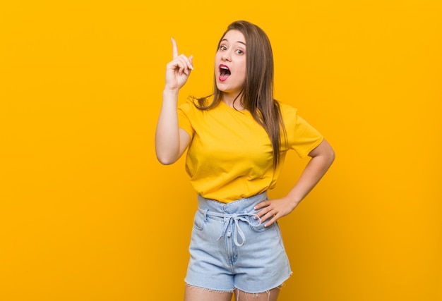 Adolescente della giovane donna che porta una camicia gialla che ha un'idea, concetto di ispirazione.