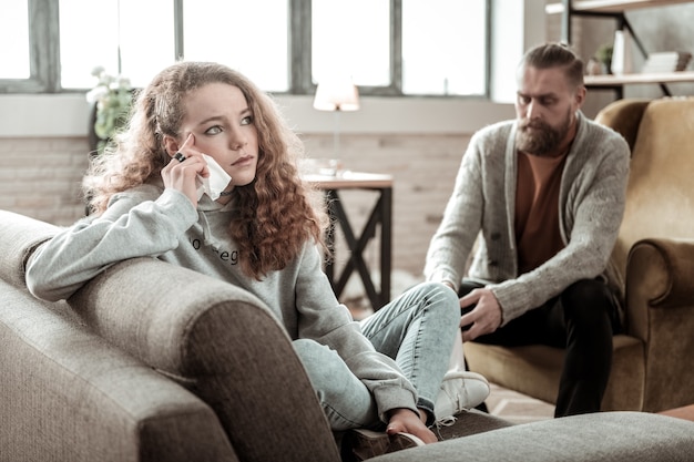 Adolescente depresso. Bella adolescente dai capelli scuri che si sente depressa parlando con un terapista privato