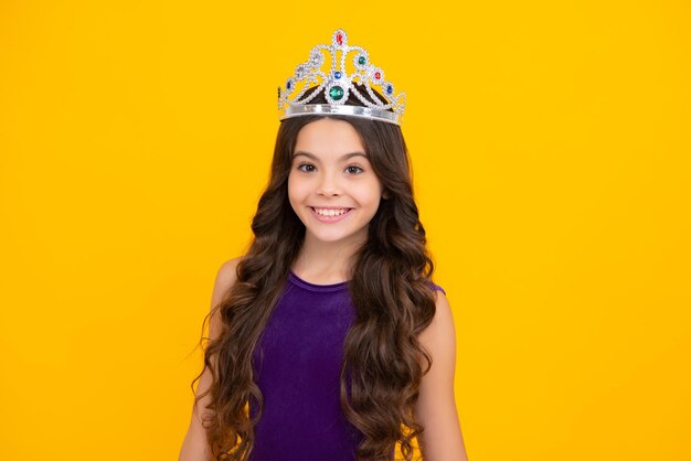 Adolescente egoista celebra la vittoria del successo Bambino adolescente nella corona della regina isolata su sfondo giallo Principessa in tiara Festa di ballo Ragazza felice faccia emozioni positive e sorridenti