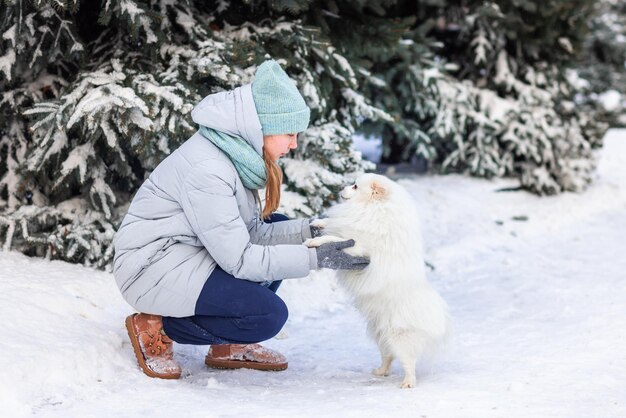 Adolescente felice divertendosi a giocare con il suo cane sulla neve in inverno