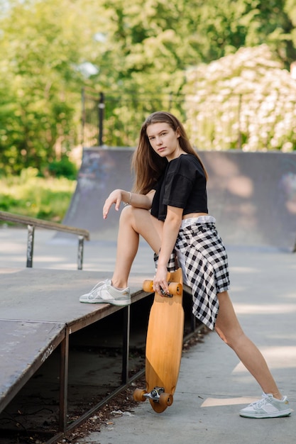 Adolescente femminile con uno skateboard che cammina sulla rampa nello skate park