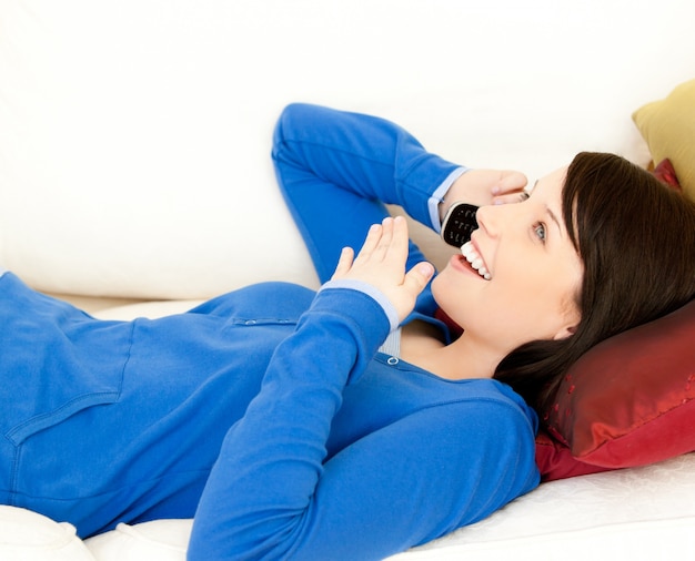 Adolescente femminile sorpreso che parla sul telefono che si trova su un sofà