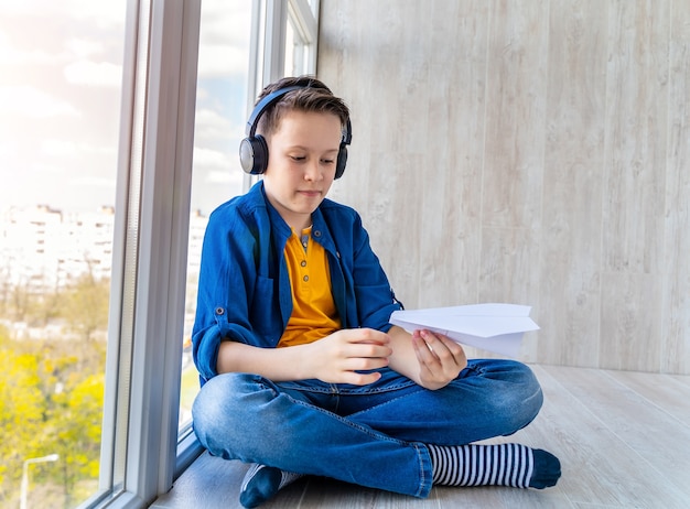 Adolescente in cuffie che ascolta la musica. Ragazzo seduto al piano in balcone. Sfondo di vista panoramica sulla città.