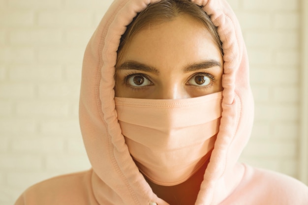 adolescente in una maschera rosa per la protezione contro il 2019-nov covid-19 a casa in isolamento sociale.