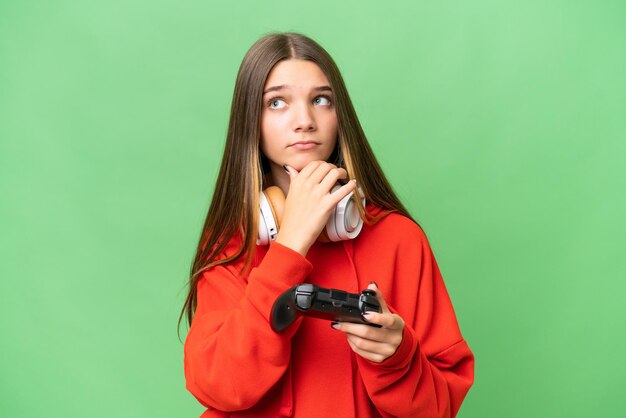 Adolescente ragazza caucasica che gioca con un controller di videogiochi su sfondo isolato avendo dubbi