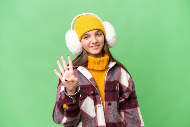 Adolescente ragazza caucasica indossando manicotti invernali su sfondo isolato felice e contando quattro con le dita