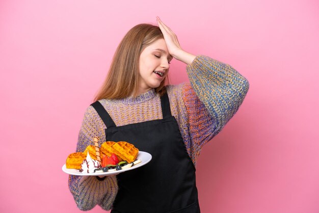 Adolescente ragazza russa che tiene un waffle isolato su sfondo rosa ha realizzato qualcosa e intende la soluzione