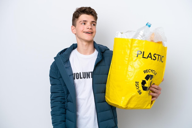 Adolescente russo in possesso di un sacchetto pieno di bottiglie di plastica da riciclare su sfondo bianco ridendo