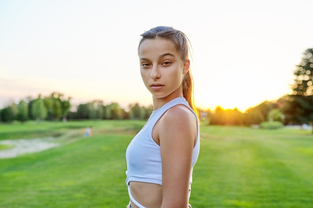 Adolescente serio che esamina la macchina fotografica nel parco sul prato