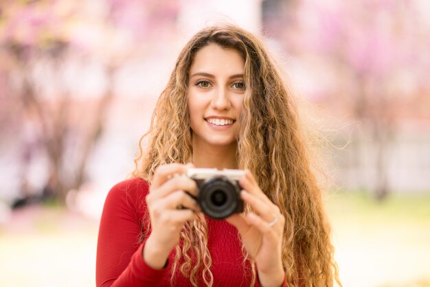 Adolescente sorridente che utilizza una macchina fotografica in un parco