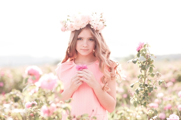 Adolescente sorridente con capelli ricci e corona di rose all'aperto