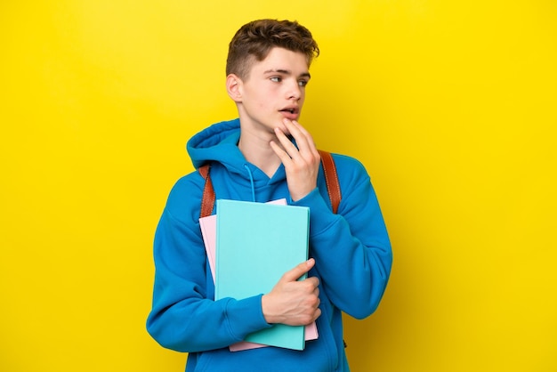 Adolescente studente russo uomo isolato su sfondo giallo alzando lo sguardo mentre sorride