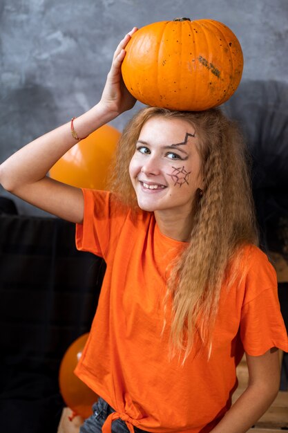 Adolescente tra le decorazioni per le vacanze di Halloween, un'enorme zucca in testa