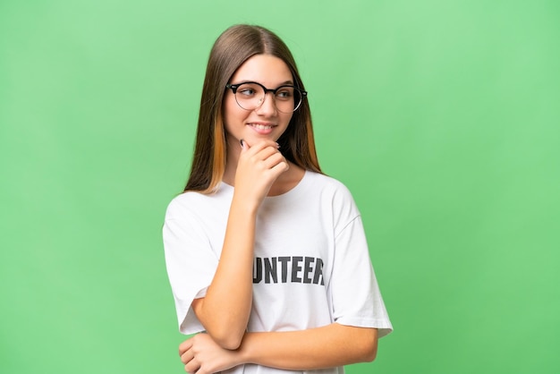 Adolescente volontario ragazza caucasica su sfondo isolato guardando al lato e sorridente