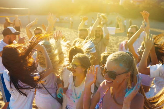 Adolescenti amici si divertono al festival di Holi festa in spiaggia celebrando le tradizionali vacanze di primavera indiane