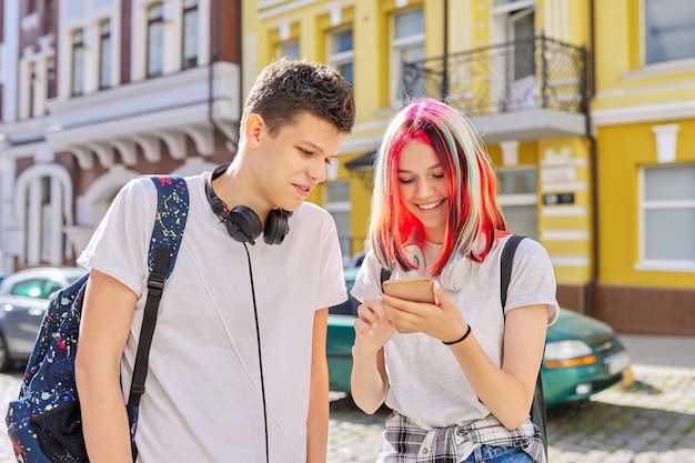 Adolescenti belli accoppiano ragazzo e ragazza insieme sulla strada della città guardando sullo schermo dello smartphone