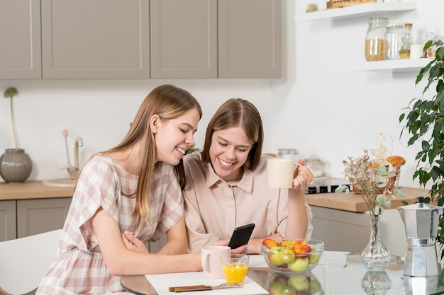 Adolescenti carine che discutono di video curiosi sullo smartphone