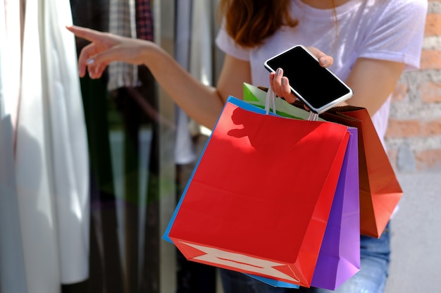 Adolescenti che tengono i sacchetti della spesa e telefono cellulare.