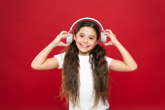 Adolescenti di musica ad effetto potente le loro emozioni percezione del mondo Ragazza ascolta musica con le cuffie su sfondo rosso Concetto di gadget moderno Gusto musicale La musica gioca un ruolo importante nella vita degli adolescenti