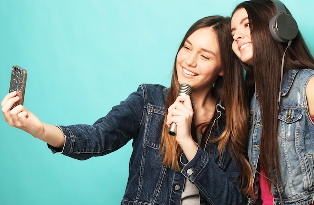 Adolescenti hipster di bellezza con un microfono che canta e scatta foto con lo smartphone