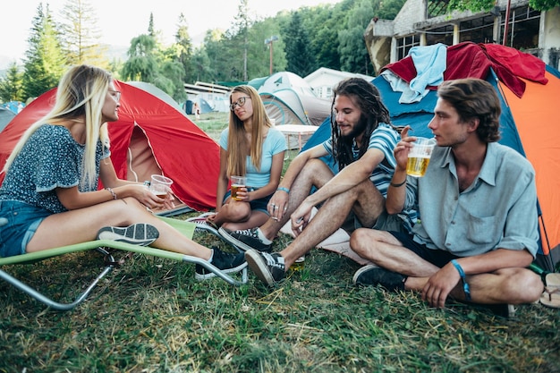 Adolescenti seduti per terra davanti alle tende durante un festival musicale