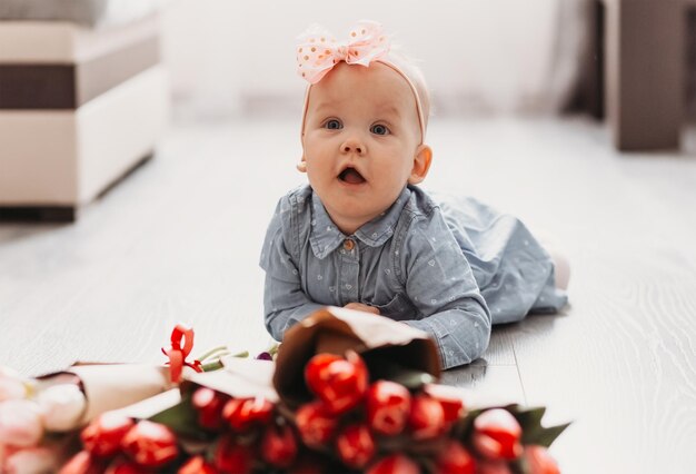 Adorabile bambina a casa con tulipani rossi concetto di festeggiare le vacanze primaverili o il compleanno