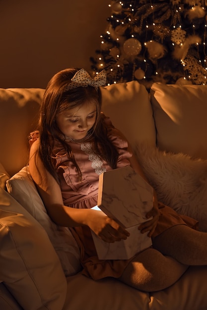 Adorabile bambina che apre un magico regalo di Natale